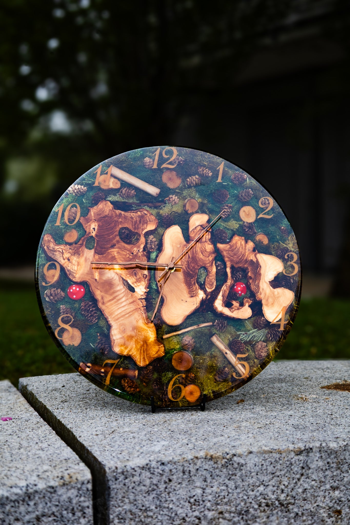Forest Whisper - Handgefertigte Wanduhr aus Olivenholz mit Moos, kleinen Zapfen und Epoxidharz.