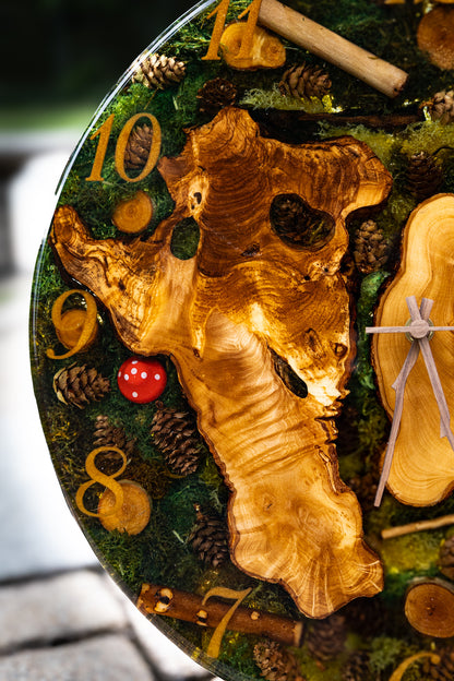 Forest Whisper - Handgefertigte Wanduhr aus Olivenholz mit Moos, kleinen Zapfen und Epoxidharz.