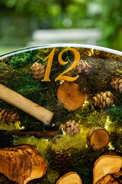 Forest Whisper - Handgefertigte Wanduhr aus Olivenholz mit Moos, kleinen Zapfen und Epoxidharz.