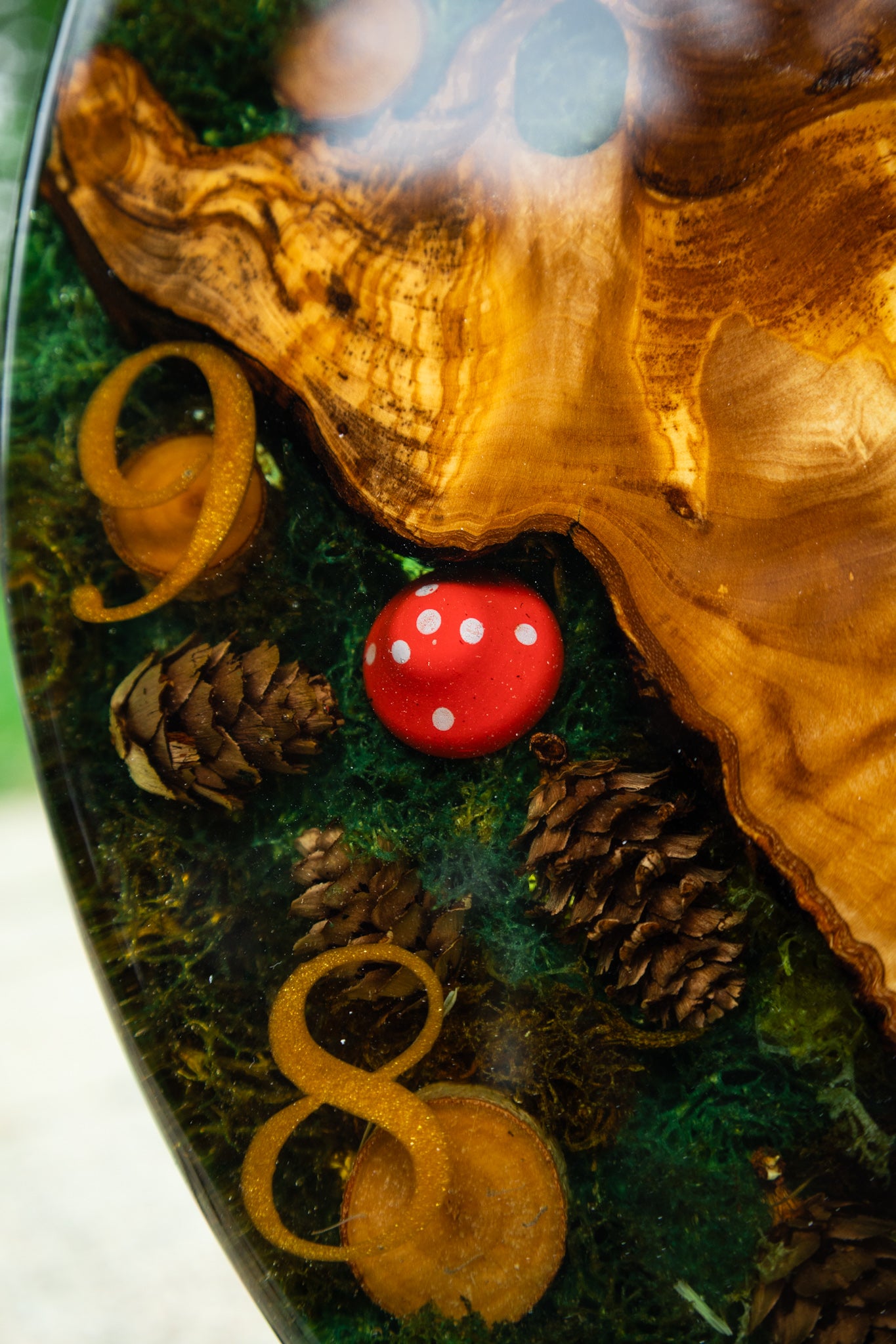 Forest Whisper - Handgefertigte Wanduhr aus Olivenholz mit Moos, kleinen Zapfen und Epoxidharz.