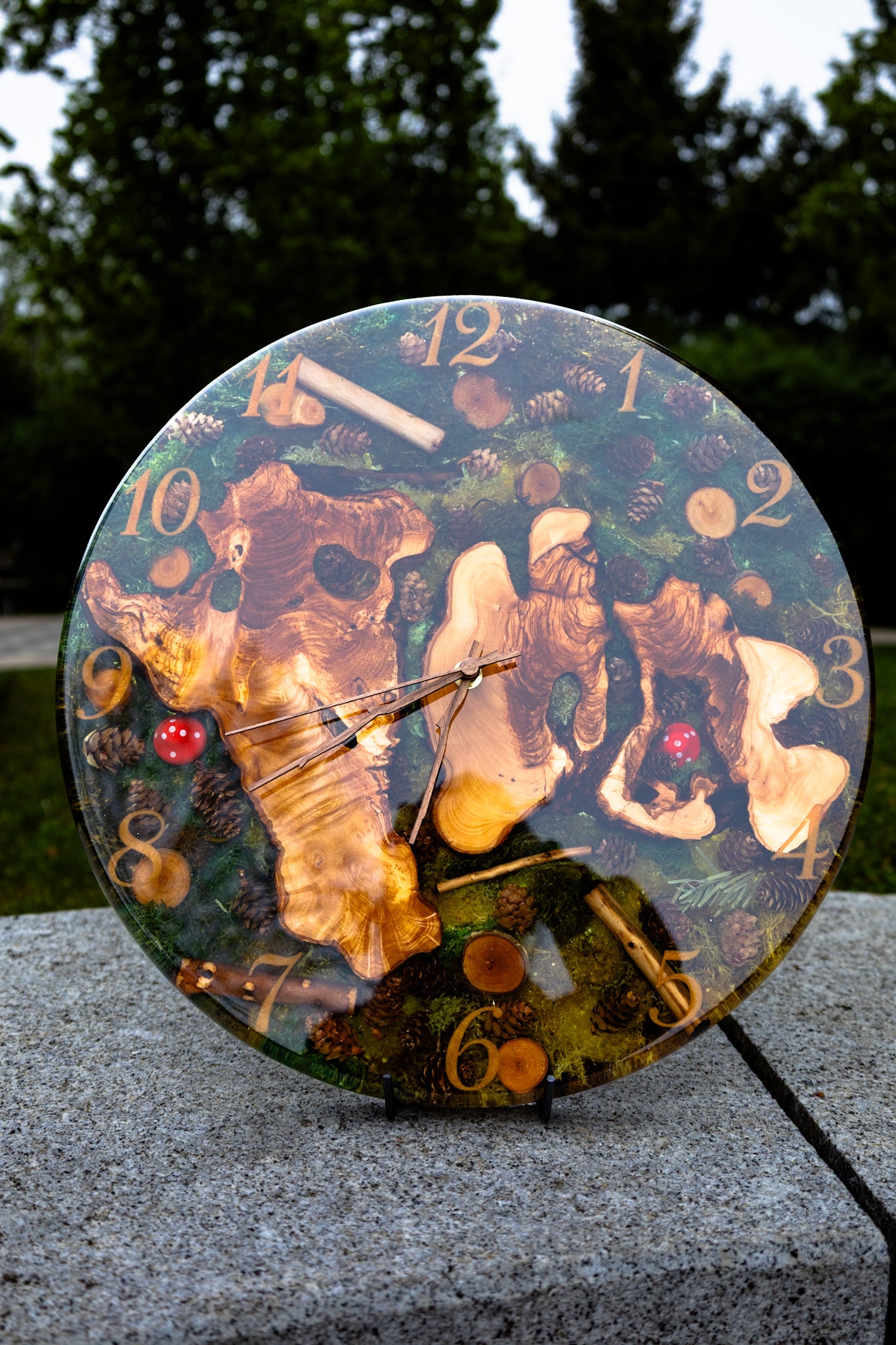 Forest Whisper - Handgefertigte Wanduhr aus Olivenholz mit Moos, kleinen Zapfen und Epoxidharz.